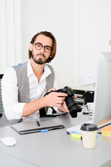 male photographer editing photography in office with a computer, camera and graphic tablet