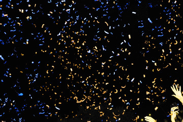 Confetti fired in the air during a beach party. Confetti are in all the image. Confetti blue and yellow