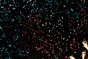 Confetti fired in the air during a beach party. Confetti are in all the image. Confetti green and red