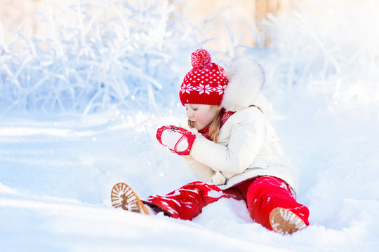 Child playing with snow in winter. Kids outdoors.