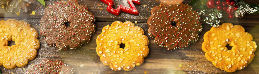 Festive cookies Christmas cooking , top view of chocolate and milk biscuits with icing sugar and Christmas ornaments on old wooden background