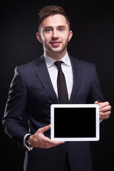 Picture of serious businessman standing with tablet