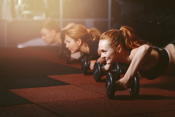 lifting. Group of athletes doing training plank ups with kettlebells in gym