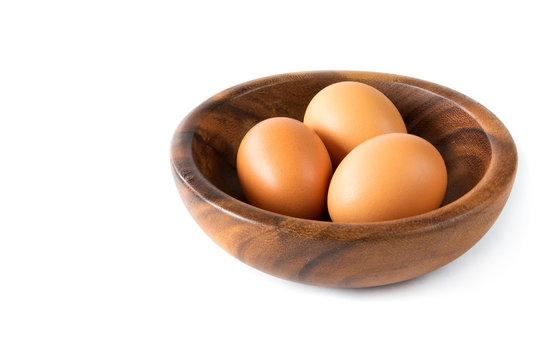 Chicken eggs brown in a wooden bowl close-up on a white background isolate