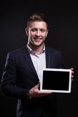 Picture of serious businessman standing with tablet