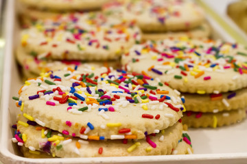 closeup of golden cookies with tiny rainbow sprinkles. Soft focus