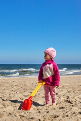 Dziewczynka bawi się na plaży łopatką do piasku. © Rajtar photography