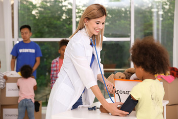 Fototapeta premium Young woman examining little cute girl. Volunteering abroad concept