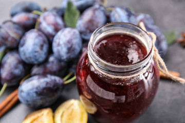 Jar of tasty plum jam on table