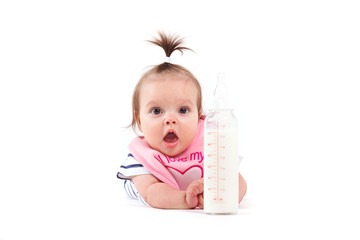 cute confused baby girl in white shirt and pink bib holds bottle