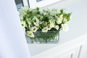 Vase with beautiful eustoma flowers on window sill