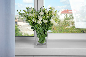 Vase with beautiful eustoma flowers on window sill
