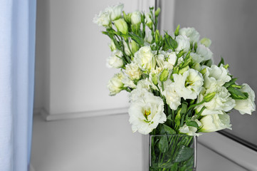 Vase with beautiful eustoma flowers on window sill