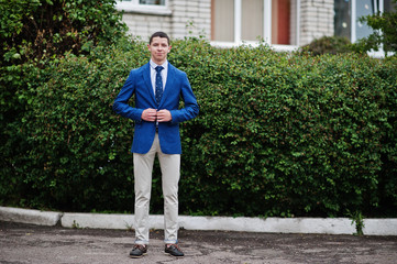 Portrait of a fashionable and stylish high school graduate in elegant tuxedo posing outdoor with bushes on the background. © AS Photo Family