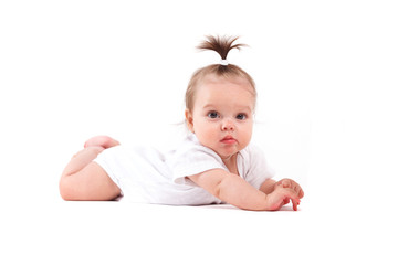 cute beautiful baby girl in white shirt lies on tummy with milk bottle