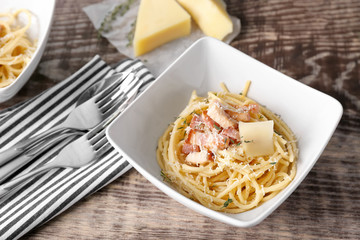 Bowl of pasta carbonara with bacon on wooden table