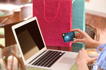 Woman with laptop and credit card at table, closeup