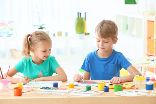 Cute children painting pictures at table indoors