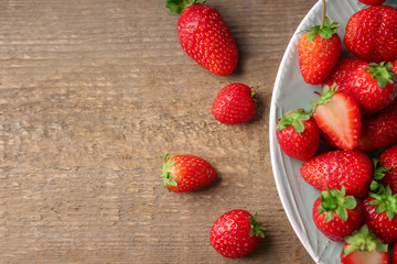 Plate with fresh strawberries on wooden background