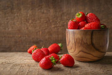 Fresh strawberries on wooden table and in bowl