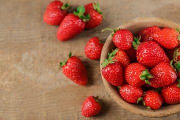 Bowl with fresh strawberries on wooden table