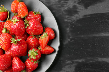 Plate with fresh strawberries on dark background
