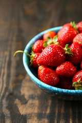 Bowl with fresh strawberries on wooden table