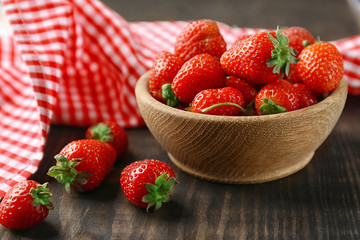 Bowl with fresh strawberries on wooden table