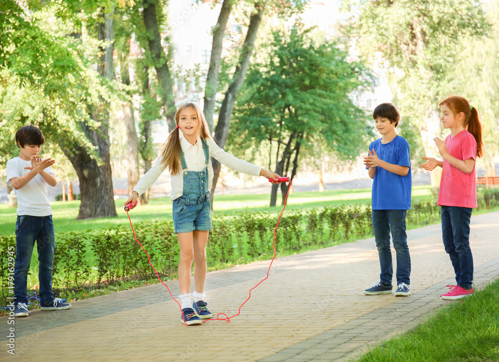 Wall mural cute little children jumping rope in park