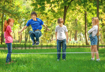 Cute little children jumping rope in park