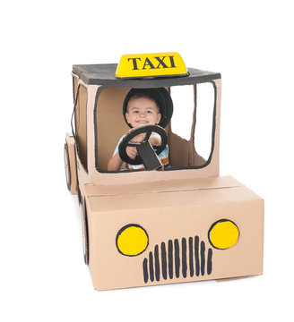 Little boy playing with cardboard taxi on white background