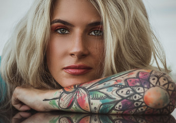 Closeup portrait of. Beautiful girl put her head in her arms with tattoos. expectation.