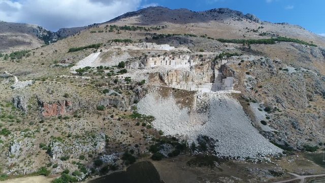 Aerial bird view footage of Marble quarry mountain area flight towards the quarry showing the large square blocks cut out of mountain and also showing the stone rubble at foot of mountain 4k quality
