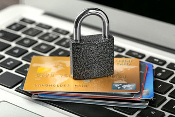 Credit cards and lock on laptop keyboard, close up