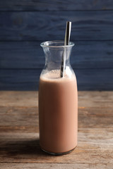 Bottle with yummy cocoa on wooden table