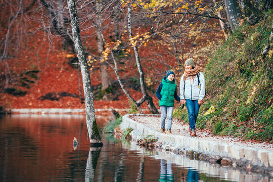 Mother and son walk in beautiful autumn park near lake