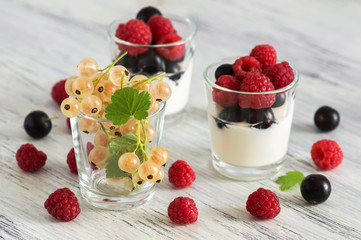 Fresh berries of raspberries and currants in a glass with yogurt. Selective focus