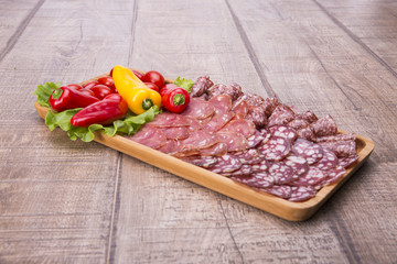 Set of meat delicatessen, tomatoes and peppers on a wooden table.