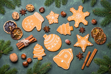 Christmas gingerbread cookies with spices and  decorations on green stone background. Top view with copy space.