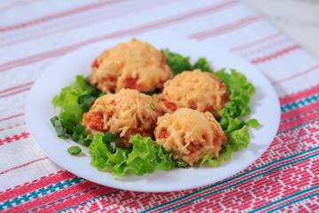 Meat cutlet with carrots and cheese on a white plate with greens