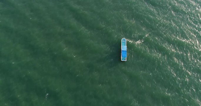 Aerial view blue boat sails on shallow turquoise ocean
