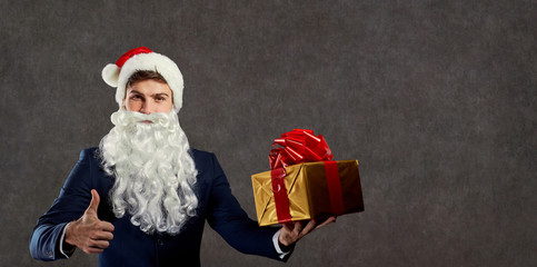 Businessman in Santa Claus costume with a gift in his hand. Concept of gift ideas for Christmas.