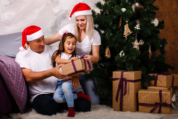 grandfather, granddaughter, mother near the Christmas tree