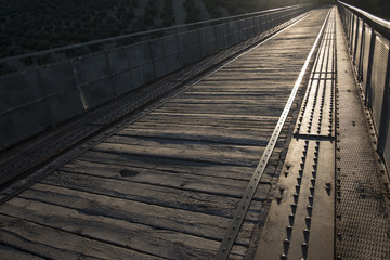 Old railway bridge of pedestrian wooden boards at sunset