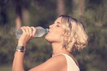 Girl drinks water in a summer park in nature 