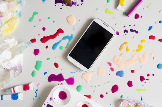 Smart phone on surface filled with colors