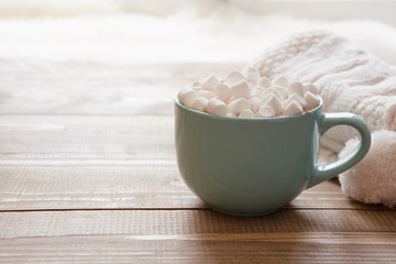 Blue cup of hot chocolate with marshmallow on windowsill. Weekend concept.