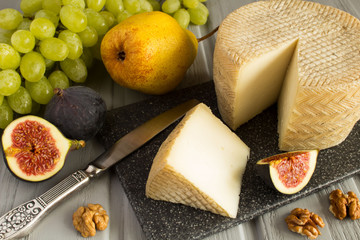 Cheese with nuts and fruits on the grey cutting board