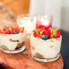 Homemade italian dessert tiramisu with strawberries, mint and blueberry in glass