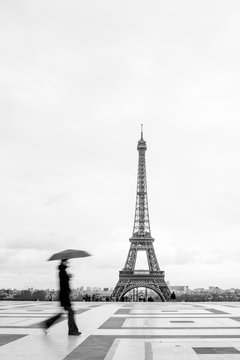 Woman with umbrella walking with the Eiffel tower in the background